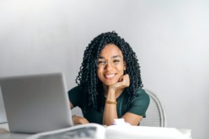Mulher negra diante do computador sorrindo