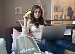 mulher sentada em um sofá fazendo compras em um computador com cartão de crédito